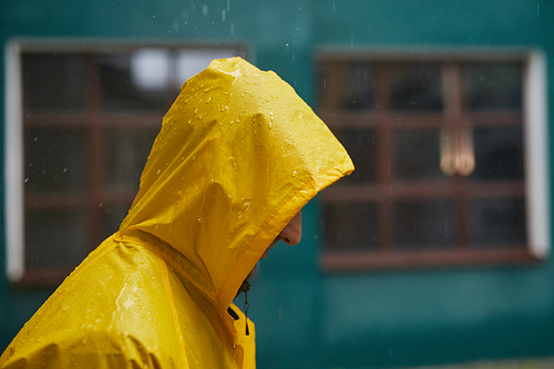 Close-up side view shot of unrecognizable man wearing yellow raincoat standing outdoors on rainy day