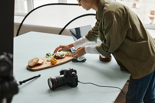 Cropped shot of female food photographer setting up gourmet bruschetta with props in studio, copy space