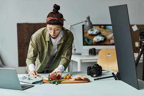 Front view portrait of female food photographer arranging gourmet setup with props, digital creator concept