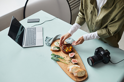 High angle view at female food photographer arranging gourmet dish with props while working in studio, copy space