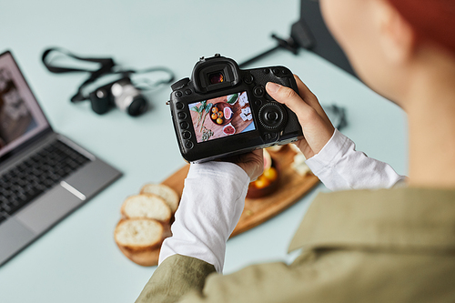 Close up of food photographer working in home studio, focus on digital camera with image on screen, copy space