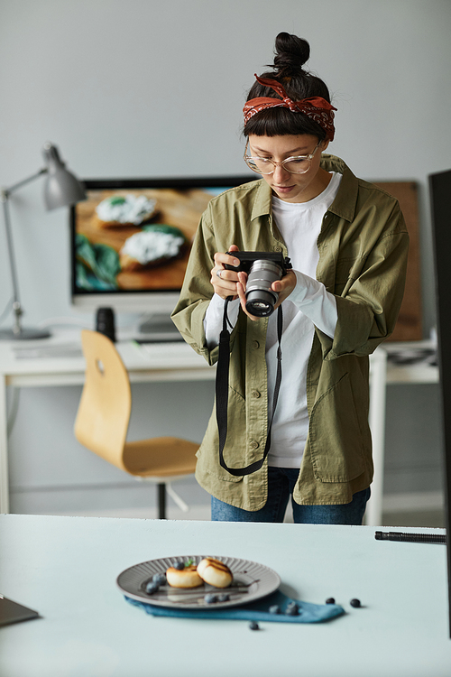 Vertical portrait of young food photographer taking pictures in studio, digital creator concept