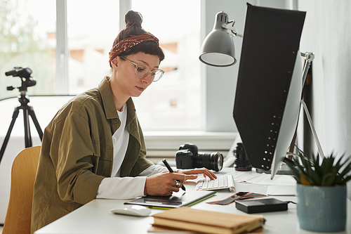 Side view portrait of female food photographer using computer while editing photos in studio, copy spac