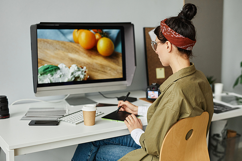 Portrait of young female photographer editing pictures at workplace in studio using pen tablet, copy space