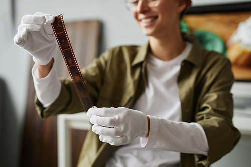 Close up of young female photographer holding film roll in studio while wearing cotton gloves, copy space