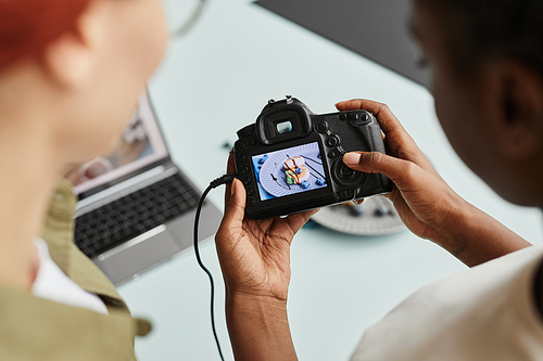 Top view close up of female photographer holding camera and looking at pictures on food on screen, copy space