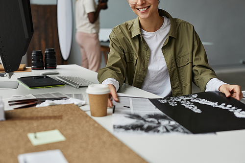 Cropped shot of female photographer looking at photo prints while working in studio, copy space