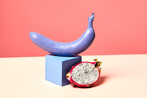 Minimal shot of single purple banana set on podium against pink background with tropical dragon fruit, girly lifestyle and dieting concept, copy space