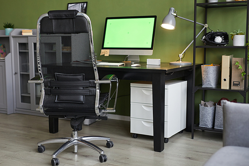 Background image of home office workplace with chroma key computer screen on desk against green wall, copy space