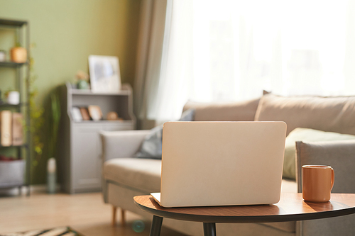 Minimal background image of opened laptop in cozy living room interior lit by sunlight,copy space
