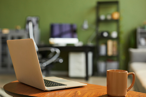 Background image of opened laptop and coffee mug in cozy living room interior, copy space