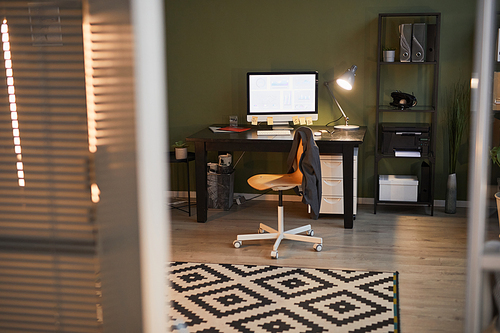 Background image of cozy office space with workplace lit by lamps late in evening, copy space