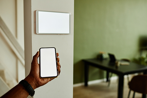 Minimal close up African American man holding phone with blank screen while connecting to smart home system, copy space