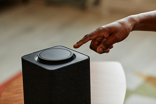 Minimal close up of male hand pushing button on smart speaker with home AI, copy space