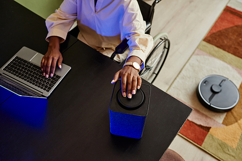 Top view of young black woman in wheelchair using smart speaker while working from home, copy space