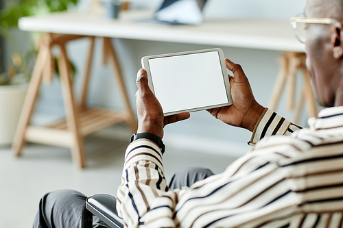 Close up of African American man in wheelchair using tablet with blank screen in minimal home interior, copy space