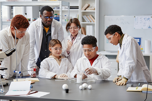 Diverse group of children wearing lab coats in chemistry class while enjoying science experiments