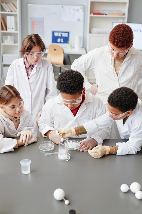 High angle view at diverse group of children enjoying science experiments in chemistry class and wearing lab coats