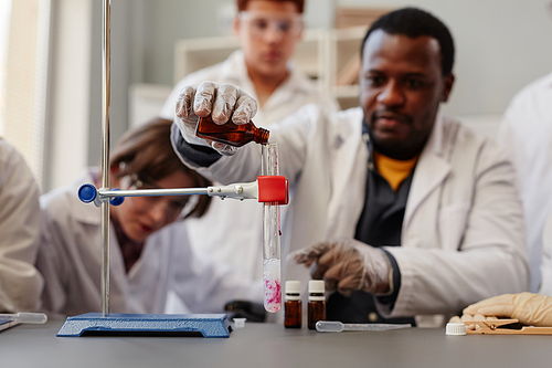 Close up of African American teacher demonstrating science experiments in school chemistry lab, copy space