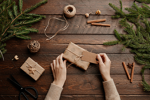 Top view Christmas background with young woman wrapping presents at wooden table, close up