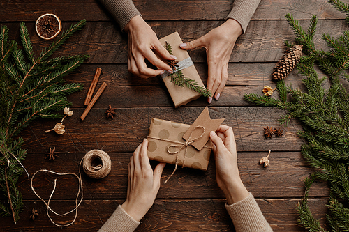 Top view background with two unrecognizable young women wrapping Christmas presents at wooden table, copy space