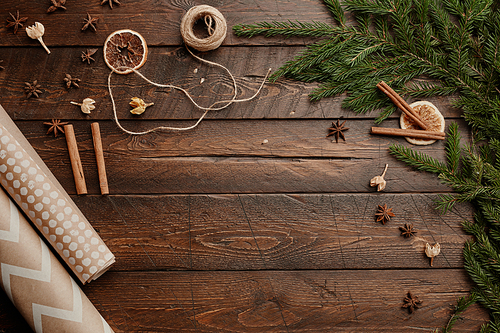 Top view background of Christmas gift wrapping supplies on rustic wooden table decorated with fir tree branches, copy space