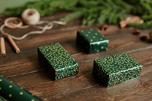 Close up background image of elegant Christmas presents wrapped in green paper on rustic wooden table, copy space