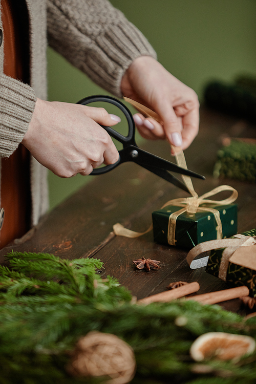 Close up of unrecognizable woman wrapping Christmas gifts at rustic wooden table, copy space