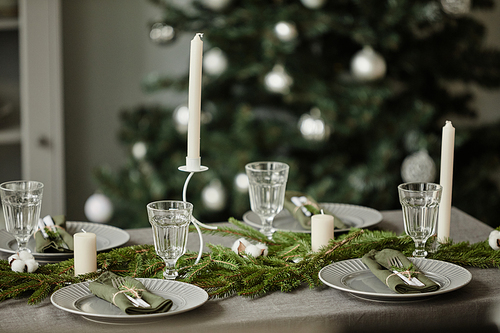 Background image of dining room table decorated for Christmas with fir tree branches and candles, copy space