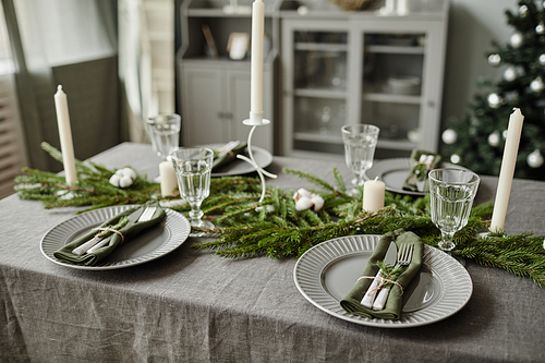High angle background image of dining room table decorated for Christmas with fir tree branches and candles, copy space