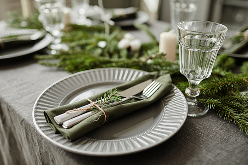 Close up background image of dining room table decorated for Christmas with fir tree branches and candles in grey tones, copy space