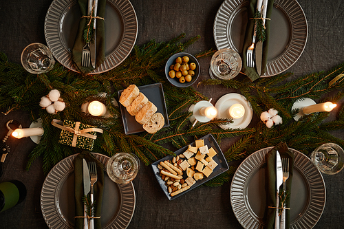 Top view background image of black table setting decorated for Christmas with candles lit, copy space