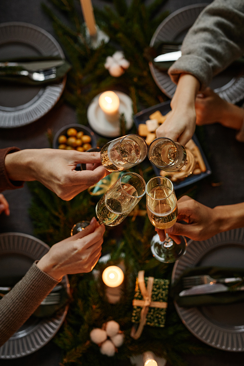 Top view background of four people enjoying Christmas dinner together and toasting with champagne glasses while sitting by elegant dining table with candles