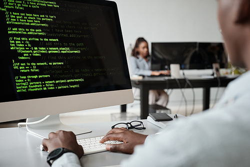 Close up of African-American software developer writing code while using computer in office, copy space