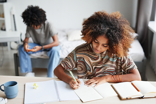 Portrait of female student doing homework and writing in notebook copy space