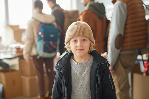 Waist up portrait of Caucasian young boy looking at camera at help center for refugees, copy space