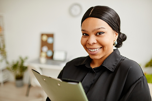 Close up portrait of successful black business woman smiling at camera while standing in minimal office