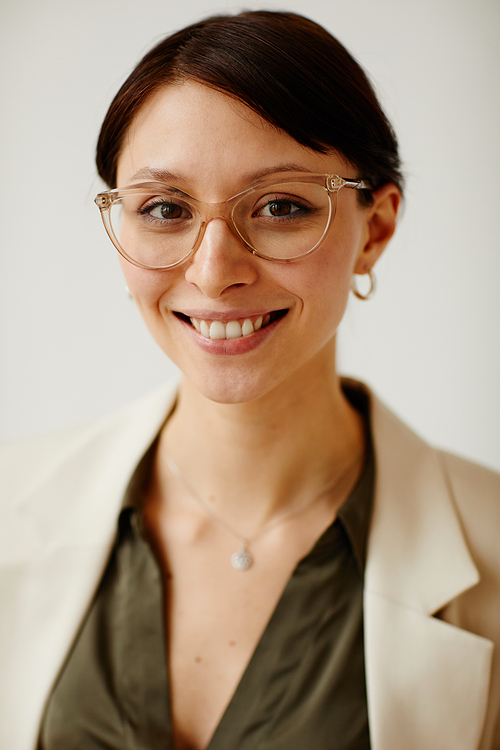 Vertical portrait of young female entrepreneur earing glasses and smiling at camera