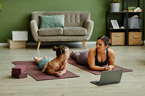 Full length shot of young mother and cute daughter with down syndrome working out at home together