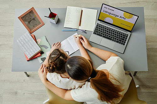 Top view at caring mother embracing daughter while studying together or doing homework, copy space