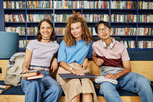 Vibrant portrait of diverse group of students in college library looking at camera and smiling