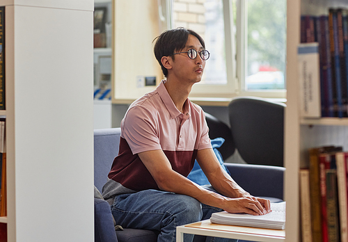 Side view portrait of blind Asian man reading book in tactile braille and wearing glasses, copy space