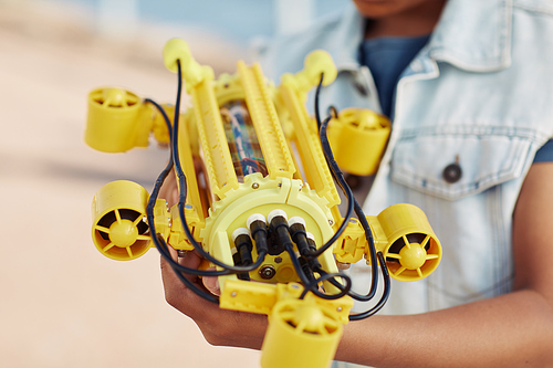 Close up of unrecognizable child holding yellow robot model, engineering for kids background