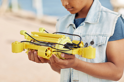 Cropped shot of young black boy holding yellow robot model, engineering for kids background