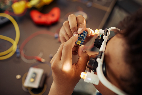 Top view closeup of black boy holding circuit board while building robot, copy space