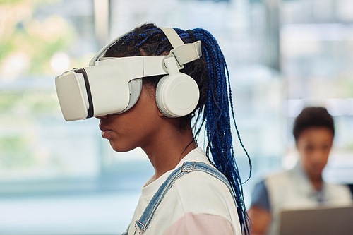 Side view portrait of black teenage girl using VR technology in engineering class