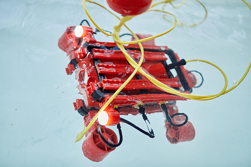 Background image or red robot submarine in water tank in engineering and robotics classroom, copy space