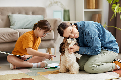 Portrait of family at home, mother and daughter playing with cute small dog on floor