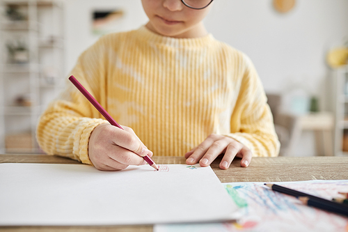 Minimal cropped shot of young girl drawing pictures while sitting at desk at home