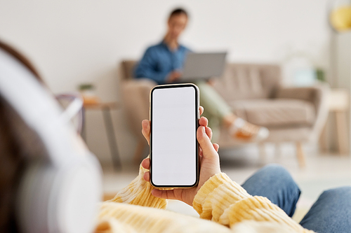 Close up of teen girl holding smartphone with white screen mockup and using internet, copy space